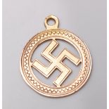 A hallmarked 9ct yellow gold swastika pendant in an oval setting with engraved decoration.