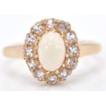 A 9ct gold Birmingham hallmarked opal and white stone ring. The cabochon opal within a halo of white