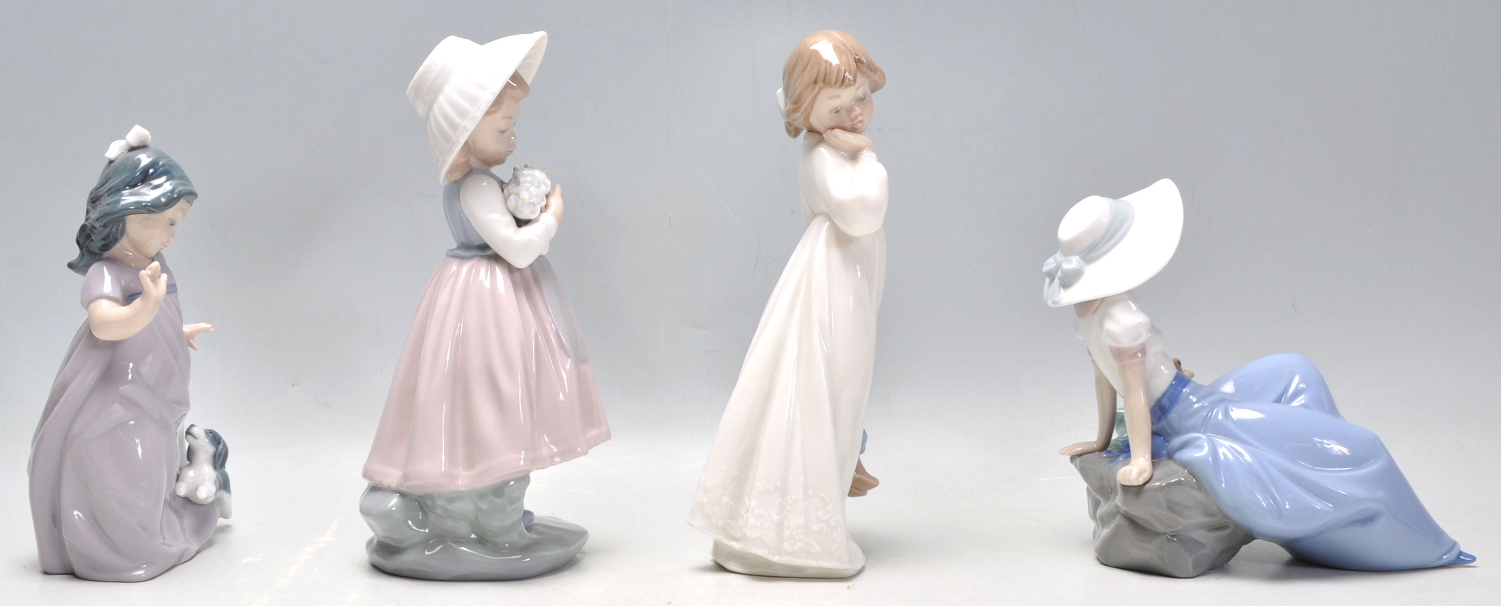 A group of four Nao porcelain figurines to include a seated girl with a perched bird, a girl in a - Image 2 of 9