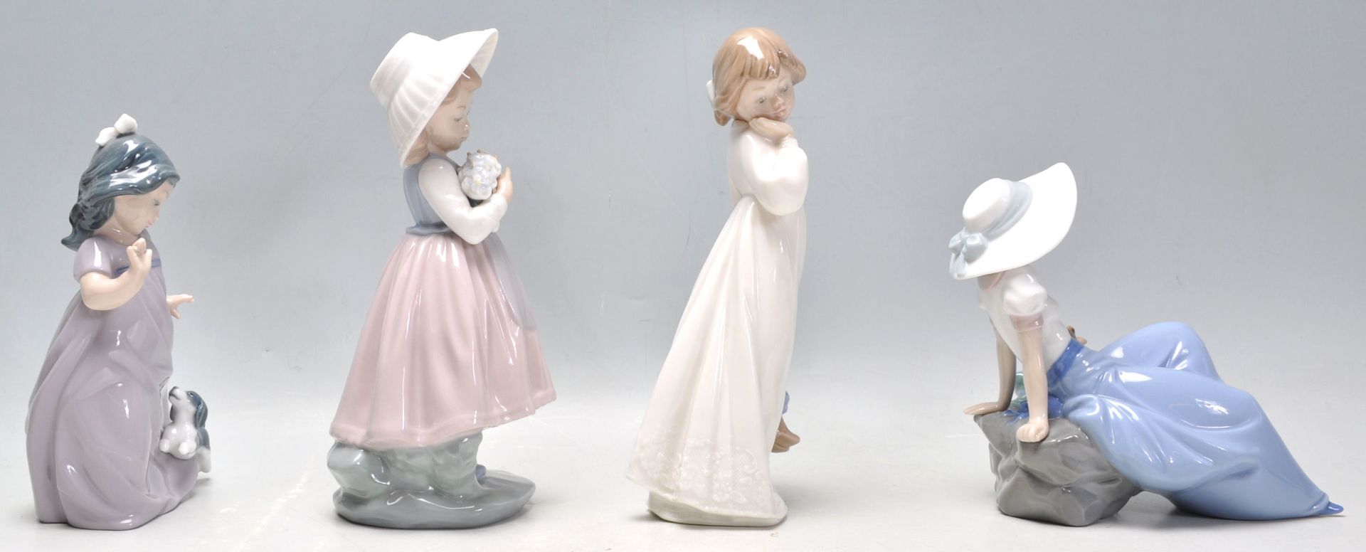 A group of four Nao porcelain figurines to include a seated girl with a perched bird, a girl in a - Bild 2 aus 9