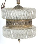 An antique style hanging ceiling light having dual press glassed top and bottom with a central brass