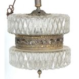 An antique style hanging ceiling light having dual press glassed top and bottom with a central brass