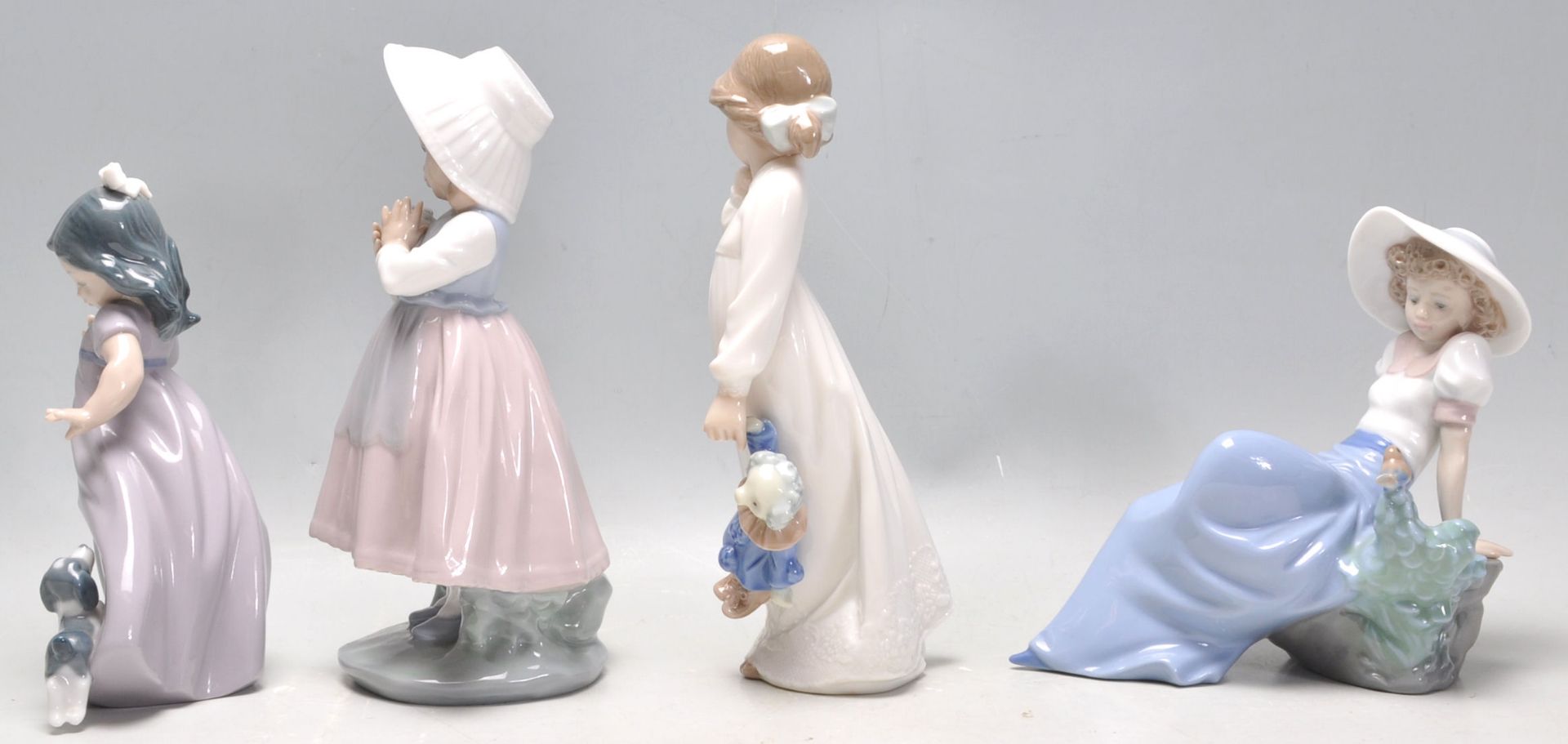 A group of four Nao porcelain figurines to include a seated girl with a perched bird, a girl in a - Bild 4 aus 9