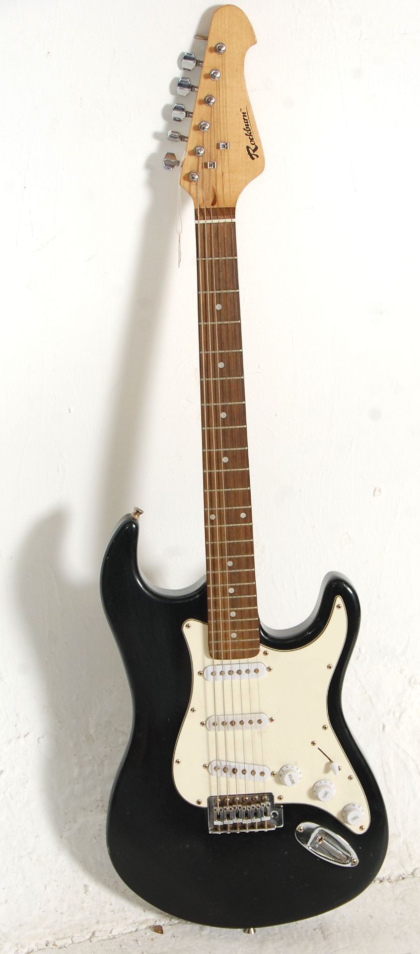 A Fender Stratocaster style Rockburn six string electric guitar having three control knobs with a