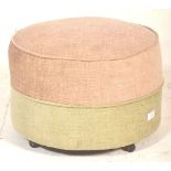 A retro mid century circular barrel foot stool pouffe in a two tone upholstered colourway of beige