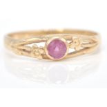 A hallmarked 9ct gold and ruby ring. The central mixed cut ruby in a pierced flower setting.