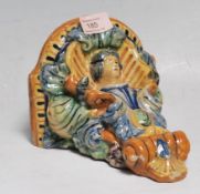 A 20th Century continental faience ceramic wall mounted shelf / sconce having a semicircular shelf