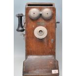 An early 20th Century wall mounted telephone being oak cased with Bakelite mouth and earpiece.