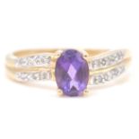 A 9ct gold hallmarked amethyst and white stone ring. The oval mixed cut amethyst with white stones