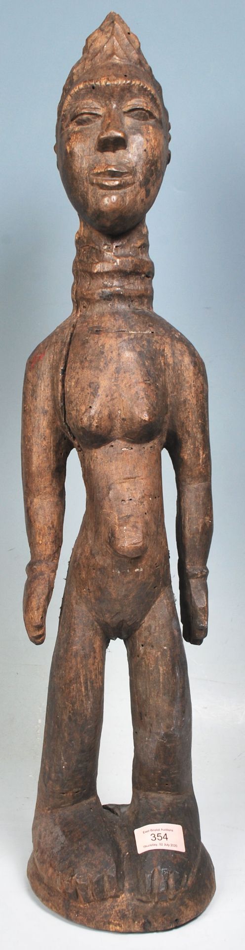 A carved African tribal wood fertility figure having a ringed neck and extended belly button, with