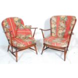 Two vintage retro 20th Century Ercol dark elm stick back open arm lounge chairs one having a round