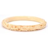 An antique early 20th Century Chinese finely carved ivory bangle with a repeating dragon motif.