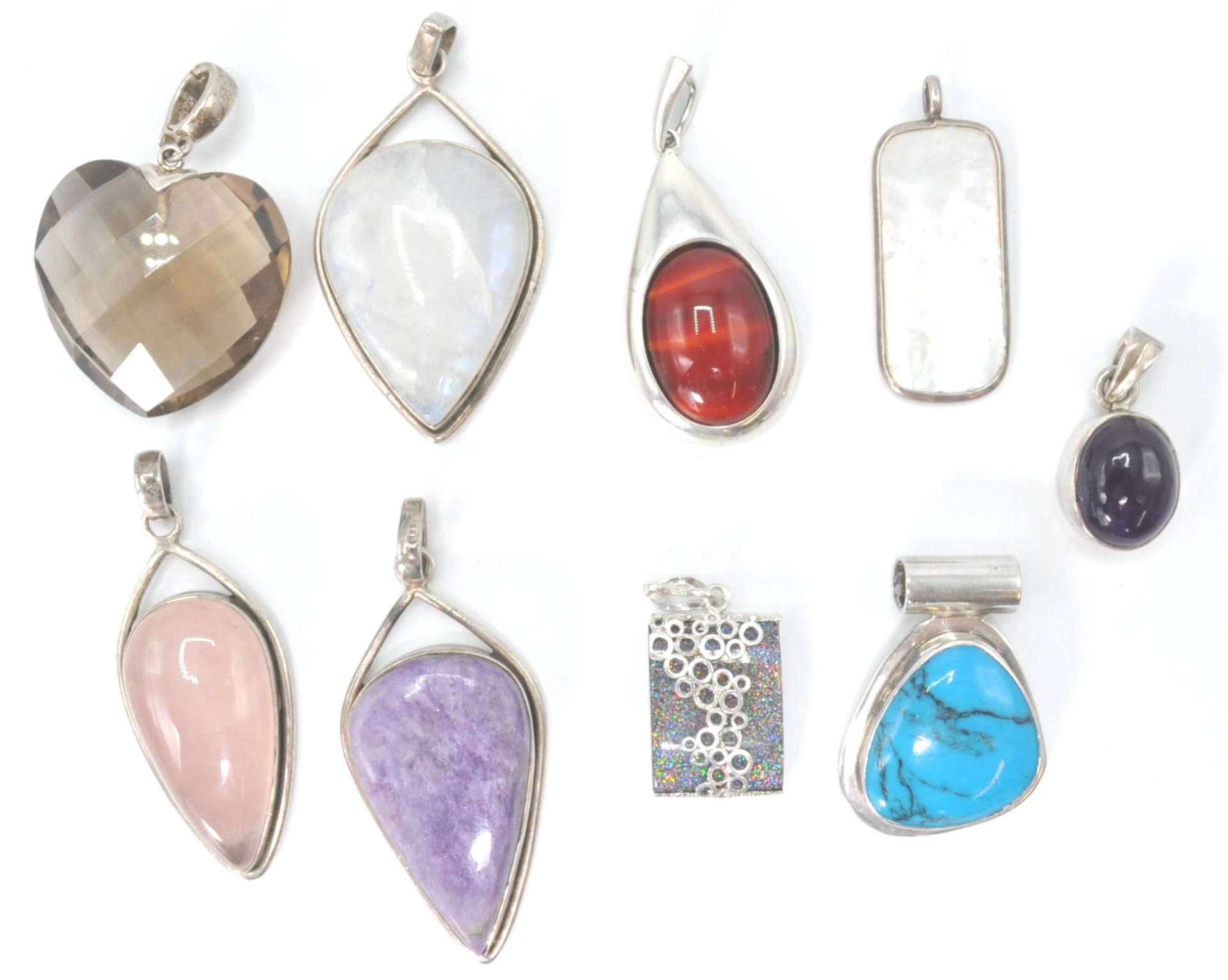 A collection of silver and agate set necklace pendants. To include turquoise, smokey quartz,