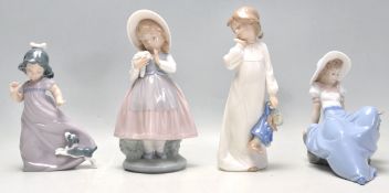 A group of four Nao porcelain figurines to include a seated girl with a perched bird, a girl in a