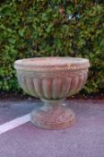 An early 20th Century reconstituted stone garden planter having a large gadrooned bowl raised on