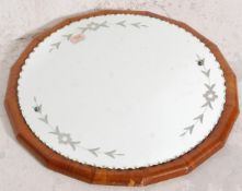 A mid 20th Century walnut veneered mirror of circular form having an applied mirror plate with