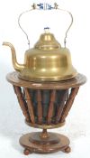 An antique early 20th Century brass kettle and warmer on a tapering wooden stand set on bun feet