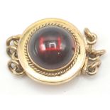 An antique 9ct gold garnet set clasp. The clasp set with a round garnet cabochon surrounded by