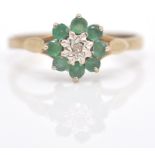 A 9ct gold emerald and diamond cluster ring. The ring with central  mixed cut diamond within a