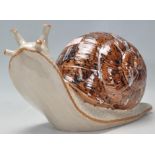 A vintage late 20th Century studio art pottery figurine in the form of a snail having a mottled