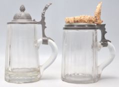 A pair of 19th century German glass steins of heavy facet cut glass design, one with stag antler