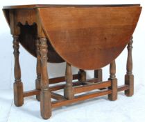 An early 20th Century country oak gate leg table raised on on block and turned legs suporting an