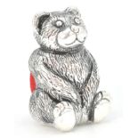 A silver plated pincushion in the form of a teddy bear with a red velvet cushion to the rear. Weighs