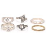 A collection of 6 silver rings to include a silver band set with 3 stones, a silver crossover band