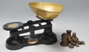 A set of antique ' The Salter ' balance scales, having an ebonised cast iron base with brass tray