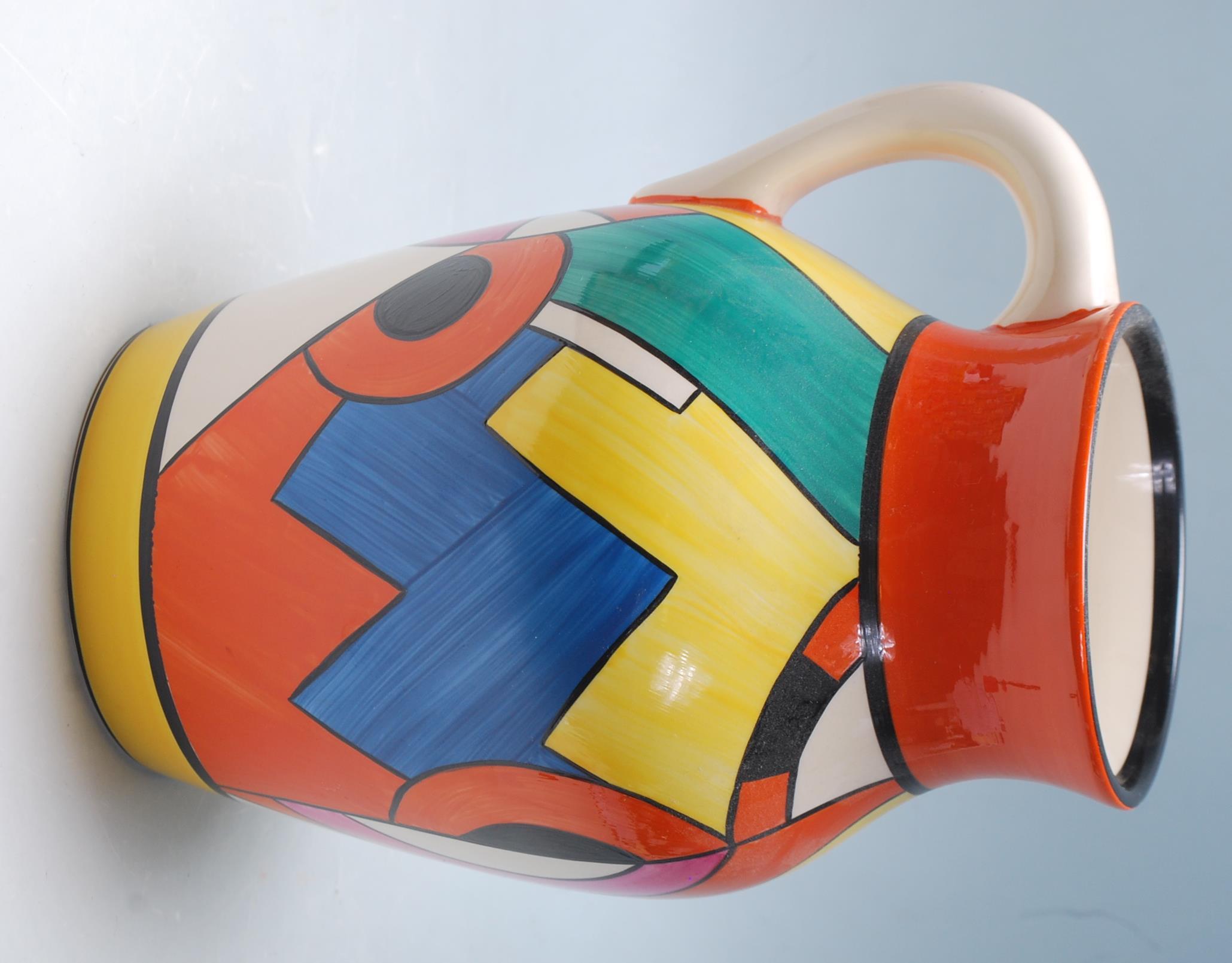 A Wedgwood Bizarre by Clarice Cliff Blue 'W' jug being hand painted with geometric decoration to the