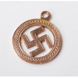 A hallmarked 9ct yellow gold swastika pendant in a circular setting with engraved decoration.