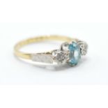 A hallmarked 18ct gold ring set with a central oval cut blue stone flanked by two illusion set white