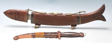 A vintage tabletop fish carving knife stand with wooden body and brass decorations, having removable