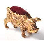 A brass cased pincushion in the form of a pot bellied pig with red velvet cushion to the back.