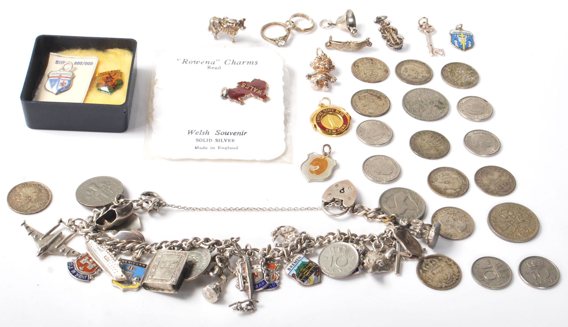 A vintage stamped sterling silver charm bracelet having various enamelled crest charms, coin charms,