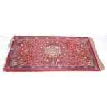 A 20th Century Persian / Islamic hall rug / carpet with a red ground featuring a central medallion
