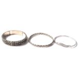 A group of three silver bangle bracelets to include a woven design band bangle (6.5 cm interior