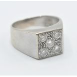 An 18ct white gold and diamond ring having a square head set with five brilliant cut diamonds on a