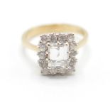 A 9ct gold and white stone cluster ring having a central rectangular cut white stone with a halo