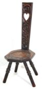A 19th Victorian welsh oak spinning chair having an ornately carved back with pierced heart to the