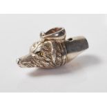 A stamped sterling silver whistle in the form of a dog being set with yellow glass eyes with a