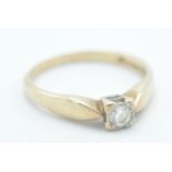 A stamped 375 9ct gold ring being illusion set with a round cut white stone in a square setting with