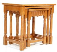 A 20th century Jacobean revival golden oak nest of graduating tables having a shaped apron being