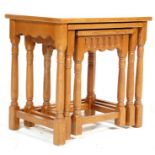 A 20th century Jacobean revival golden oak nest of graduating tables having a shaped apron being