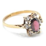 A hallmarked 9ct gold ladies dress ring being set with an oval cut red stone surrounded by six white