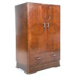 A 1930's Art Deco walnut bachelors wardrobe cabinet having twin panelled doors and a shelved
