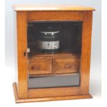 A late 19th century Victorian Art and Crafts oak smokers cabinet having a chamfered top over a