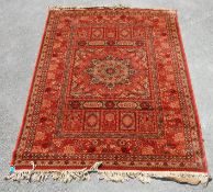 A vintage Persian Islamic rug carpet having a red background with a central star motif surround by