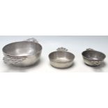 A collection of three early 20th Century pewter porringer / drinking bowls having pierced twin