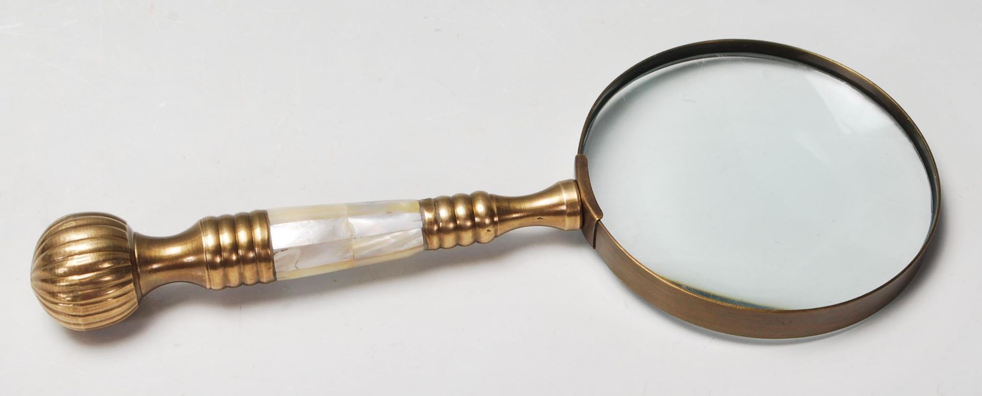 A 20th Century antique style magnifying glass having a brass and mother of pearl handle. 26cm long.